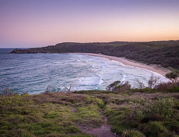 Elevated sunset view overlooking the crescent-shaped Alexandria Bay and surrounding bushland along the Noosa Coastal Track in Noosa National Park, Sunshine Coast.